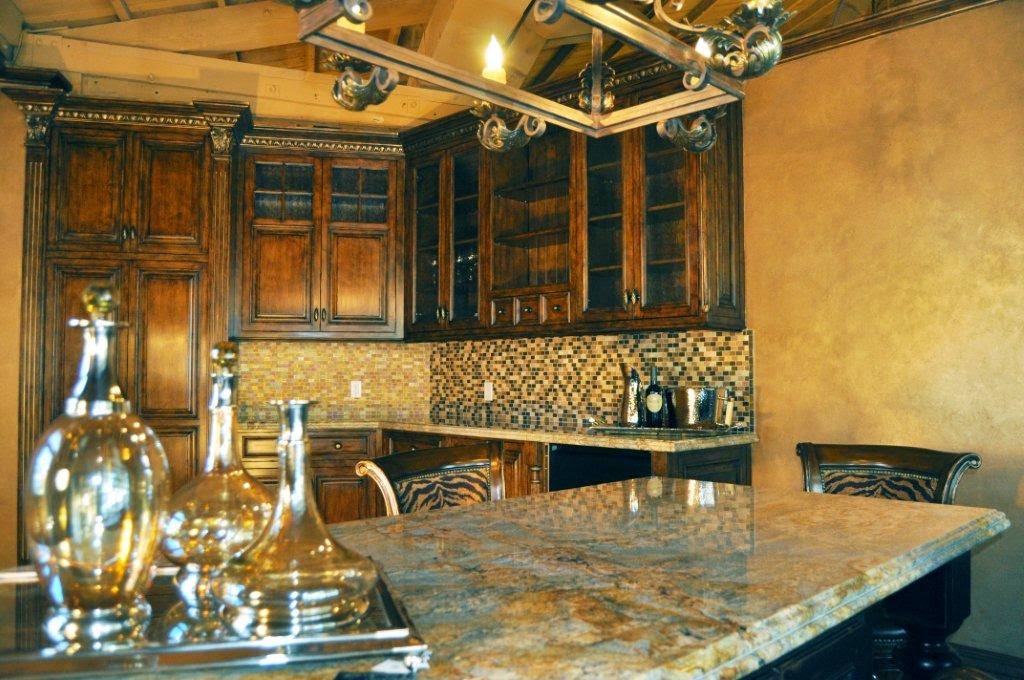 Custom wood cabinetry and mosaic tile backsplash in a private bar nook