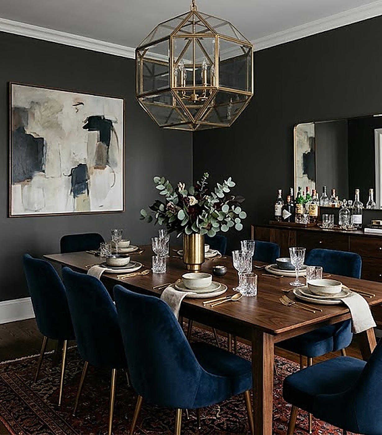 Moody charcoal dining room with a brass geometric pendant and blue velvet chairs
